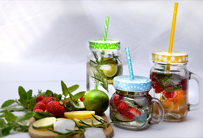 Gläser mit Früchten Wasser Zitronen Erdbeeren Kräuter Dekoration