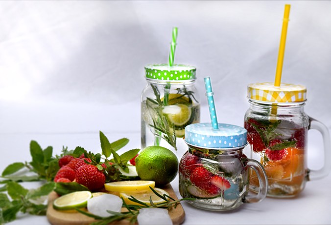 Gläser mit Früchten Wasser Zitronen Erdbeeren Kräuter Dekoration